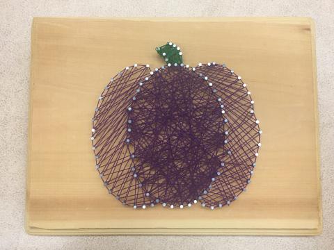 purple string art pumpkin on wooden plaque