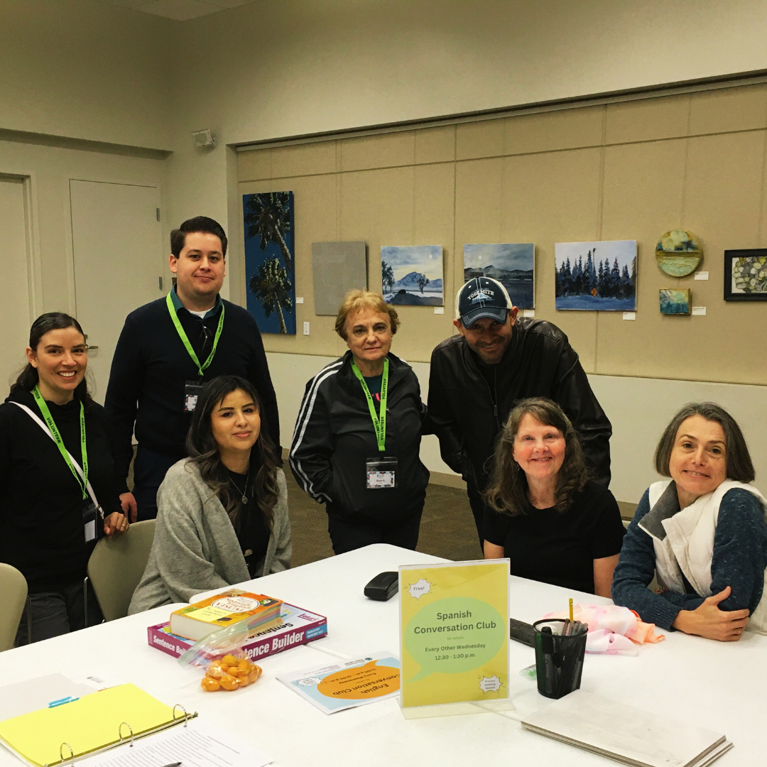 Photo of adults smiling around a table during Spanish Conversation Club